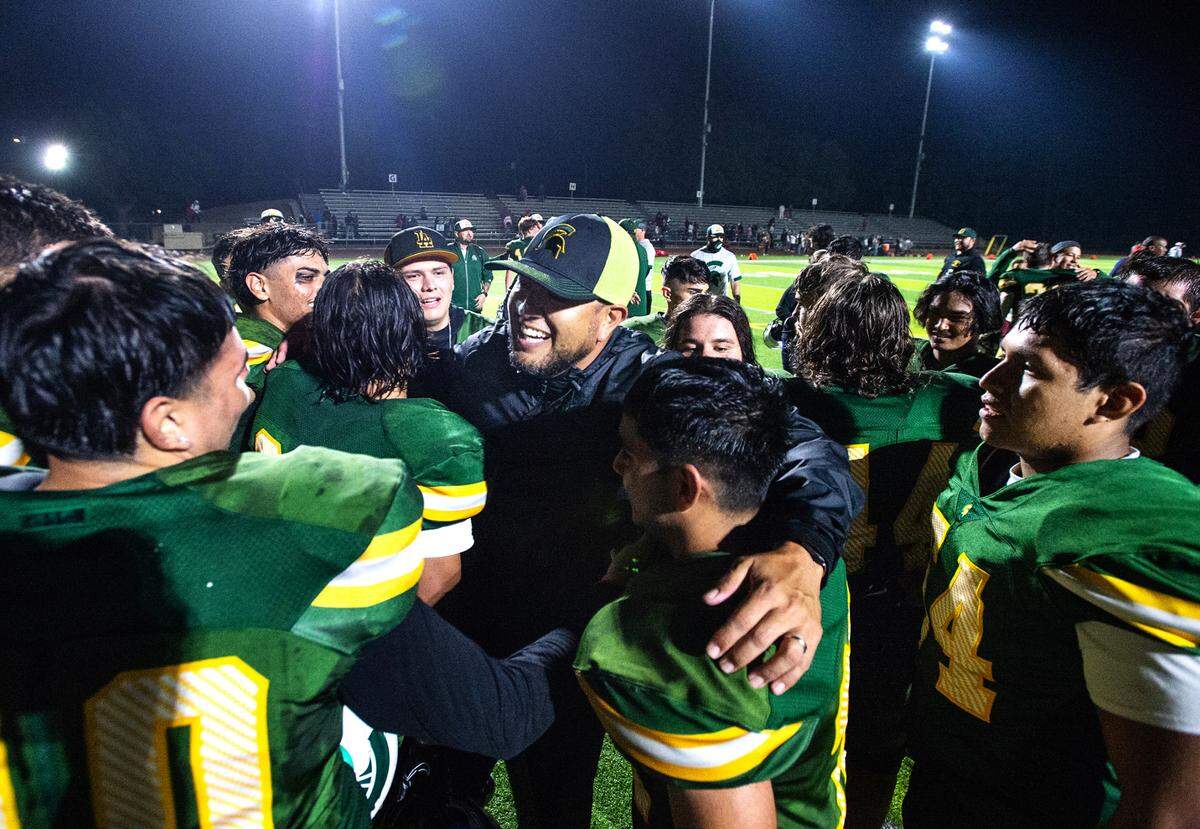 Davis coach Tim Garcia celebrates the 33-24 victory over Ceres with players in the Western Athletic Conference game at Downey High School in Modesto, Calif., on Thursday, Oct. 28, 2021.
