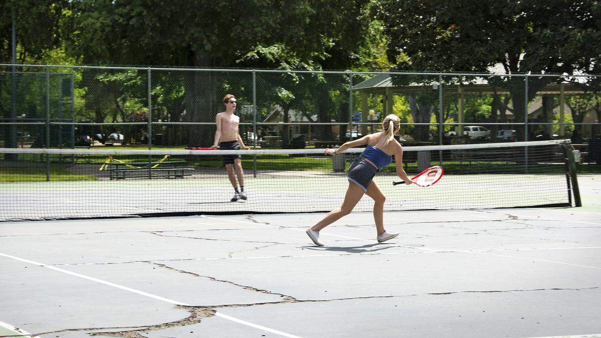 Jeffrey Peepgrass and sister Chloe Peepgrass play tennis in the newly reopened courts at Graceada Park in Modesto, Calif. April 25, 2020.