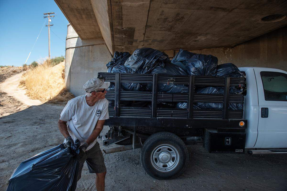 Phil McKay throws bags of garbage in a truck after volunteers picked up an estimated ton of garbage during the Operation 9-2-99 clean-up at Gateway Park in Modesto, Calif., on Saturday, July 16, 2022.