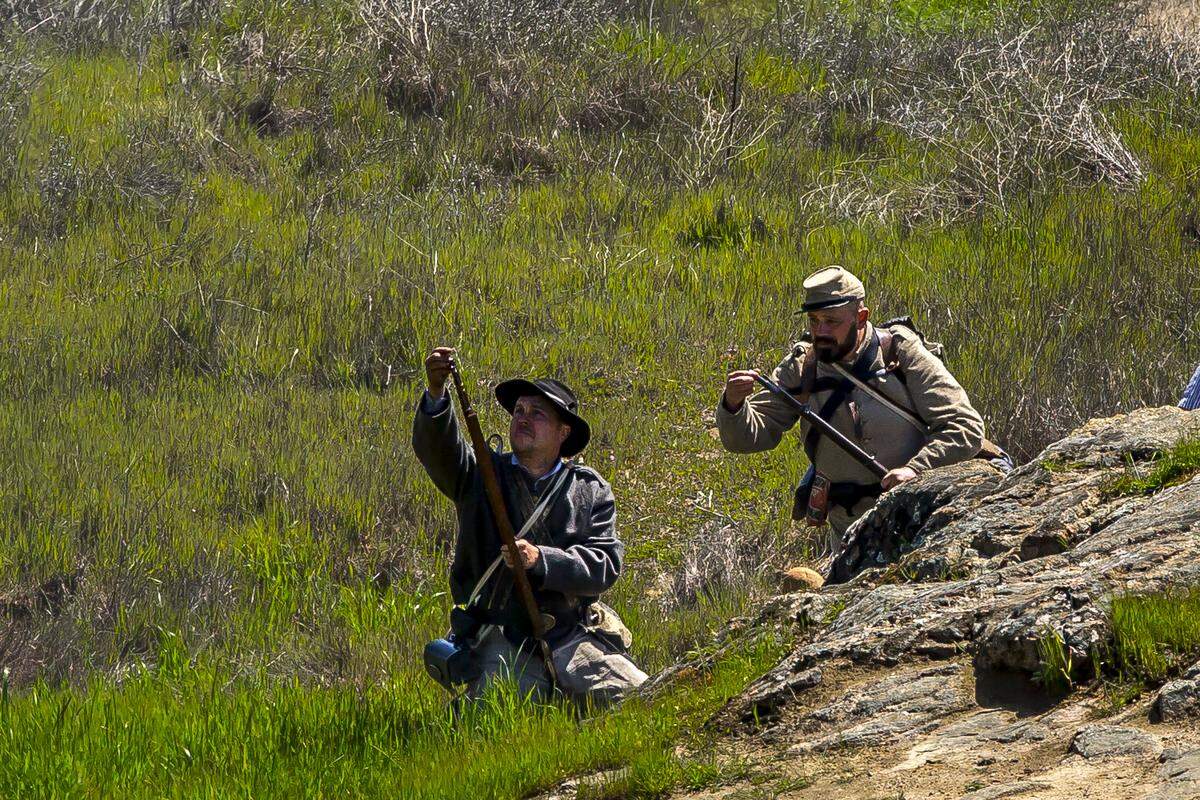 Unidentified men role-playing Confederate snipers reload during a Civil War reenactment in Knights Ferry, Calif. the weekend of March 25 and 26, 2023.