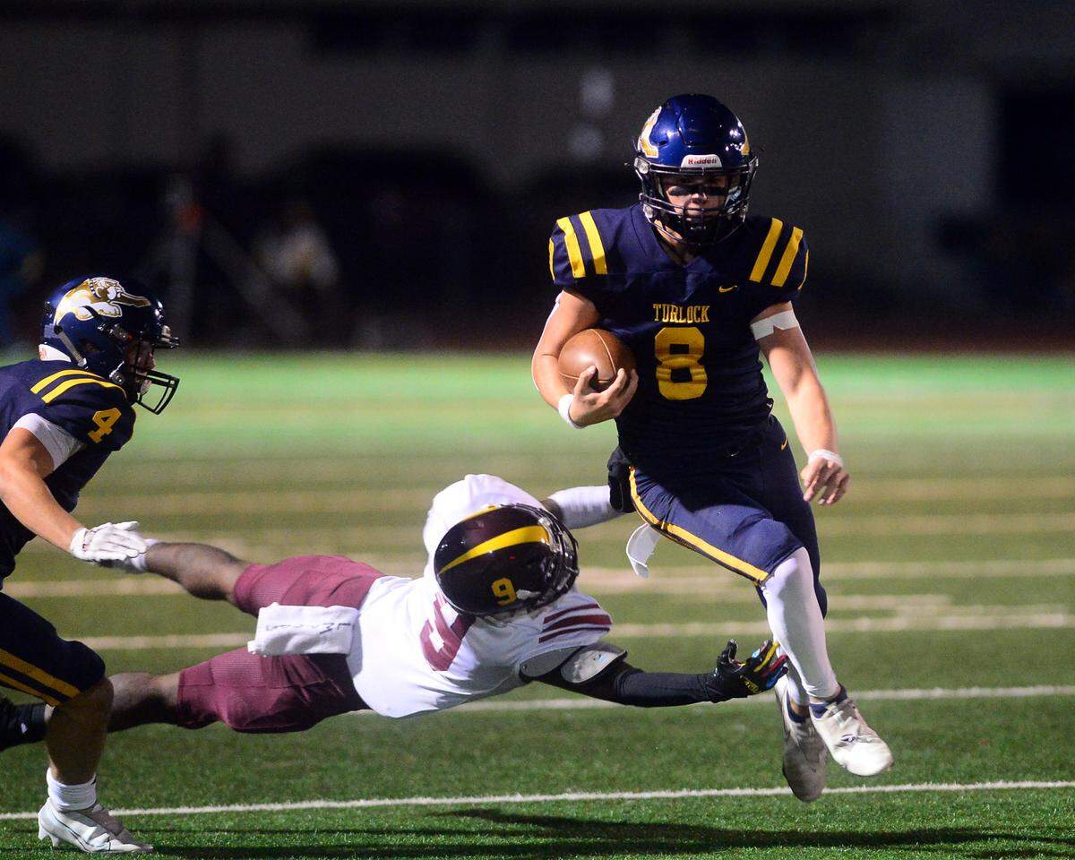 Turlock quarterback Cole Gilbert (8) skips past a defender on a scramble during a CIF Division I CIF Sac-Joaquin Section Football Playoff game between Turlock High School and Edison High School at Turlock High School in Turlock CA on November 4, 2022. Turlock won 35-0.
