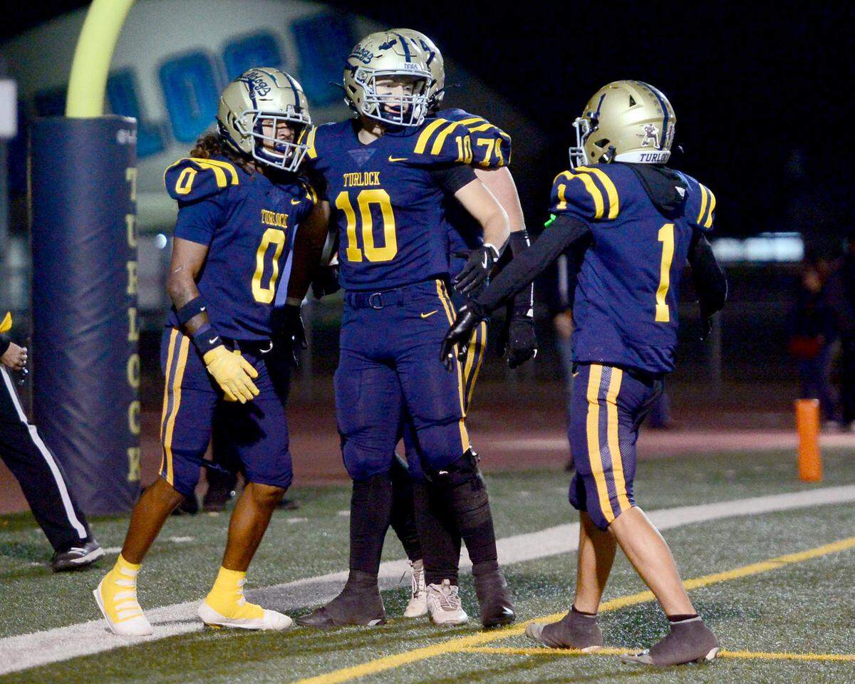 Turlocks Junior Silva (1) and Dayne Hart (10) celebrate with Jeremiah Stine (0) after Stine scored a touchdown during a Division 1 CIF San-Joaquin Section playoff game between Turlock High School and Laguna Creek High School at Turlock High School in Turlock California on November 8, 2024. Turlock won the game 48-12.
