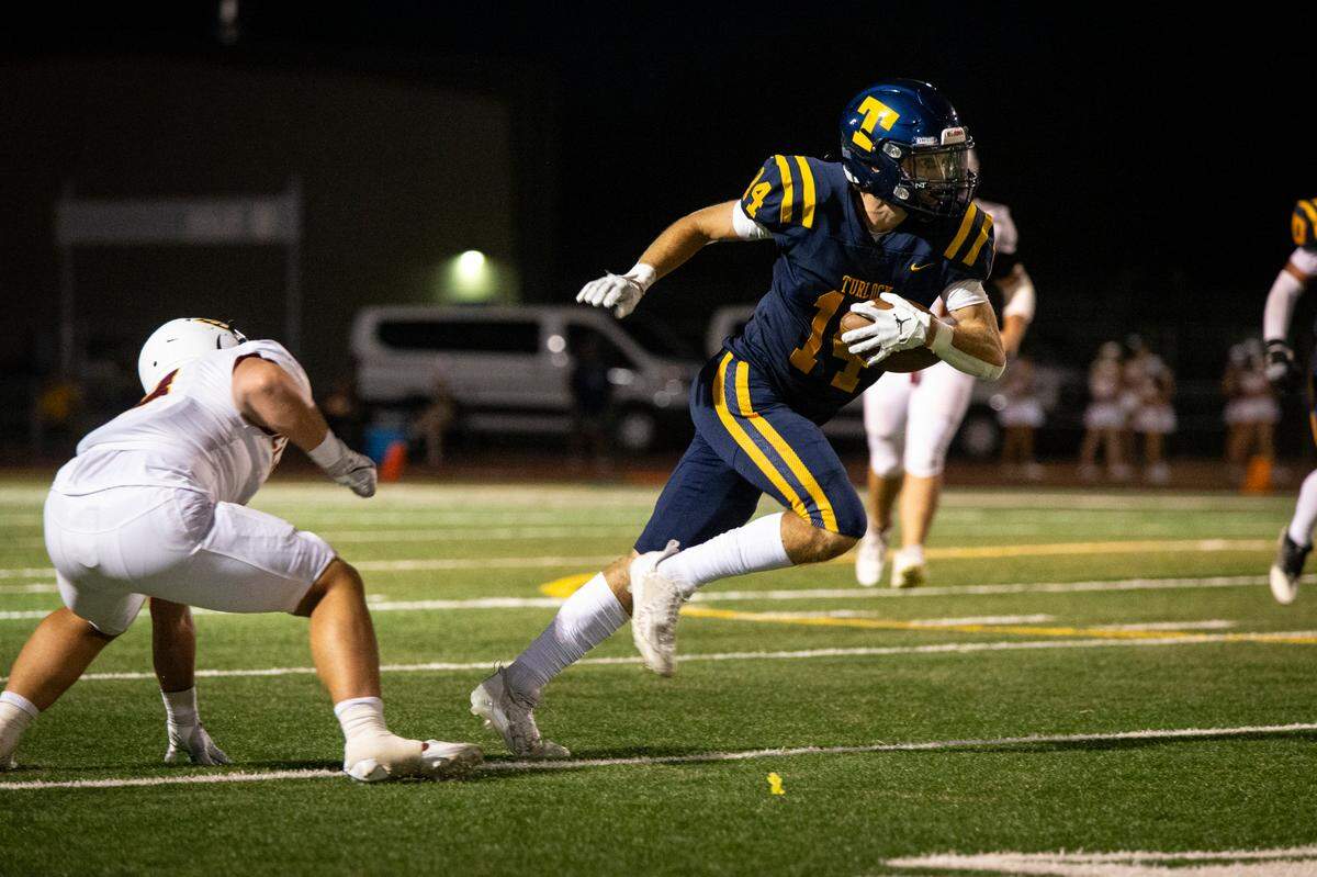 Turlock High receiver Carter Crivelli (14) works his way upfield after catching a pass during the first half of Friday night’s game against Clovis West.