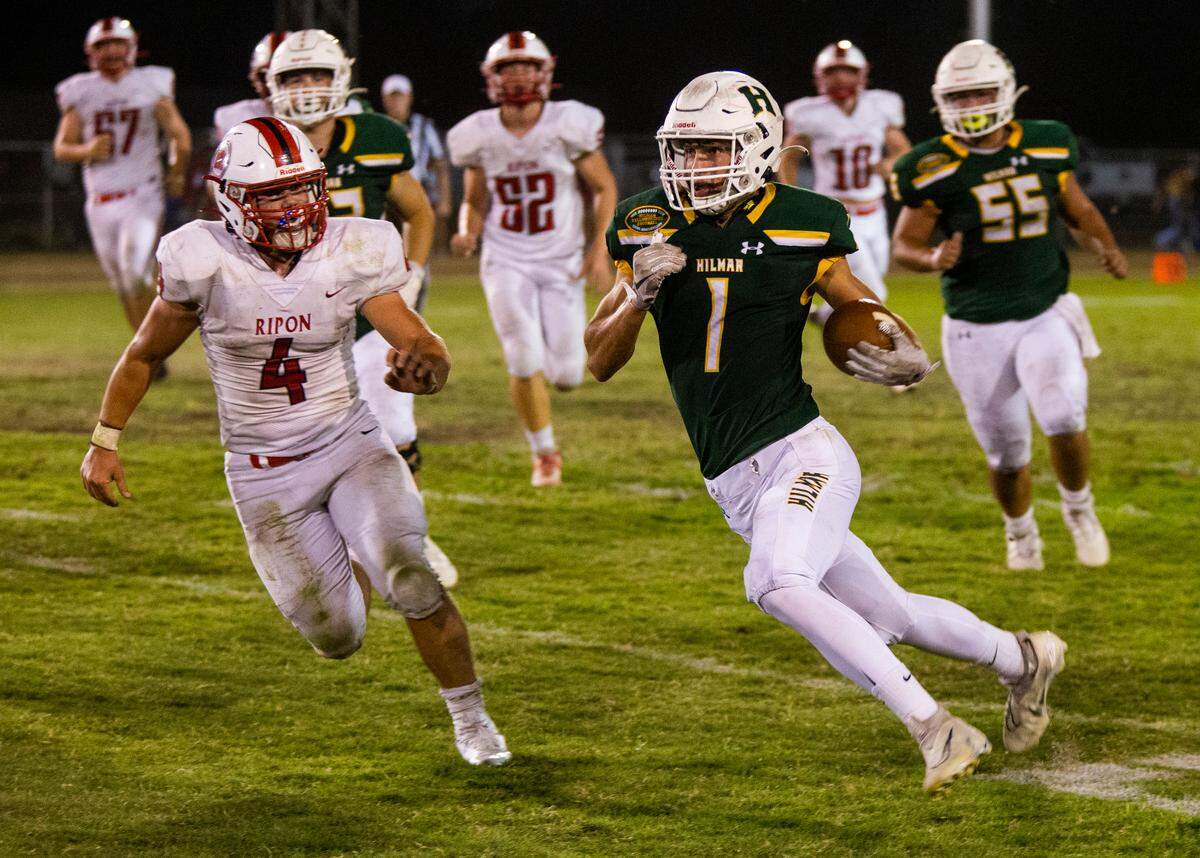 Luke Cox, 1, of Hilmar High works his way up field as Anden Ries, 4, of Ripon High closes in. Ripon vs Hilmar at Hilmar Sept. 23, 2022.