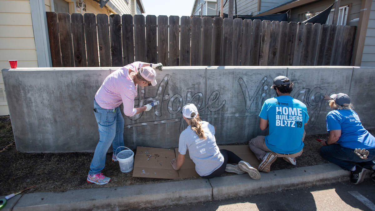 Volunteers repaint a sign at Habitat for Humanity’s Hope Village in Modesto Calif., as part of Love Modesto on Saturday, April 30, 2022.