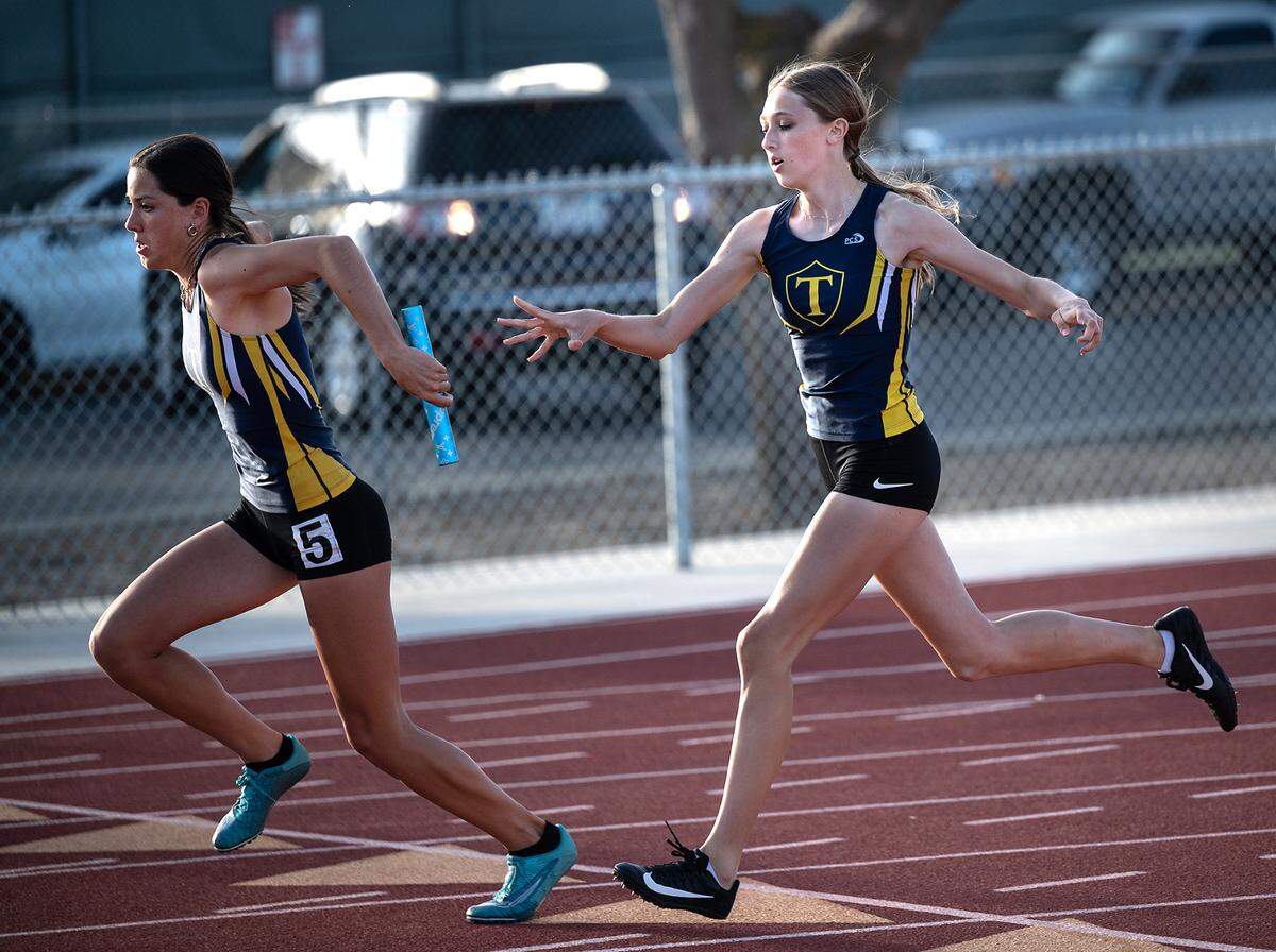 Turlock’s Shaylan Roy-Williams takes the baton from teammate Evelyn Ladine, right, for the final leg of the girls 4X100 relay at the Stanislaus County Championships on Friday, March 18, 2022, at Riverbank High School in Riverbank, Calif.