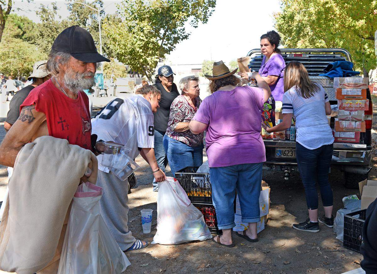 Volunteers with the Well Community Fellowship bring supplies to homeless people in Beard Brook Park on Friday afternoon Oct. 5, 2018 in Modesto, Calif.