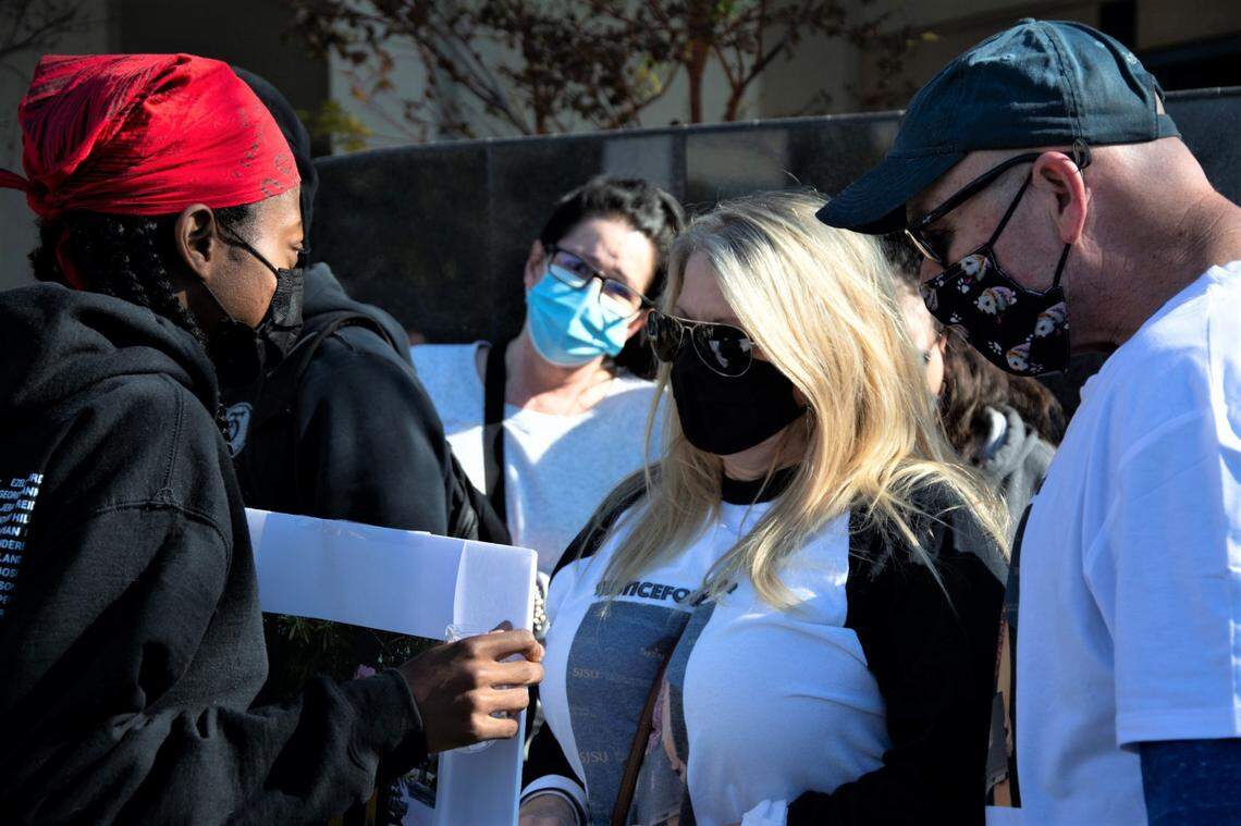 Turlock BLM co-founder Jaimee Ellison presents a sign to Darlene and Ray Ruiz, the mother and stepfather of Trevor Seever who was shot and killed by a Modesto Police officer during a protest in front of the police department in Modesto, Calif. Jan. 9, 2021.