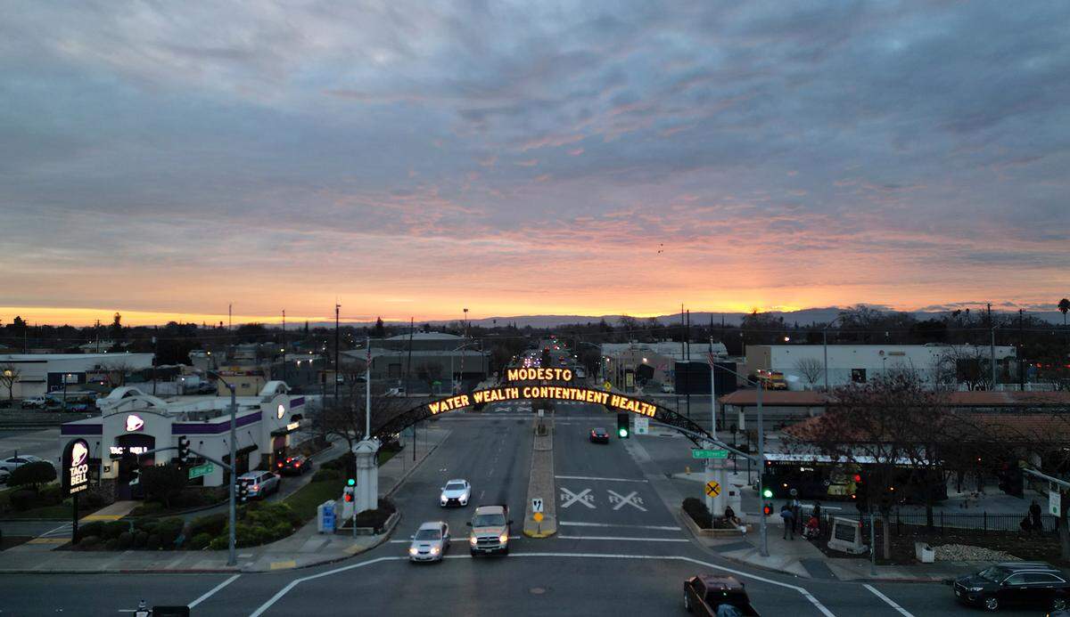 The sun sets behind the Diablo Range and the Modesto Arch in Modesto, Calif., January 12, 2024.