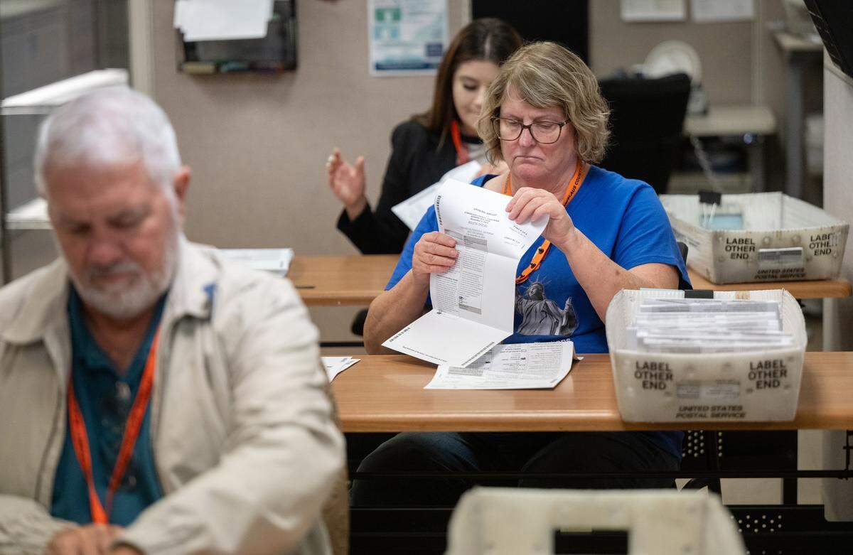 Clerk Cindy Felt, right, flattens ballots with other clerks before they are counted at the Stanislaus County Registrars of Voters office in Modesto, Wednesday, Oct. 23, 2024.