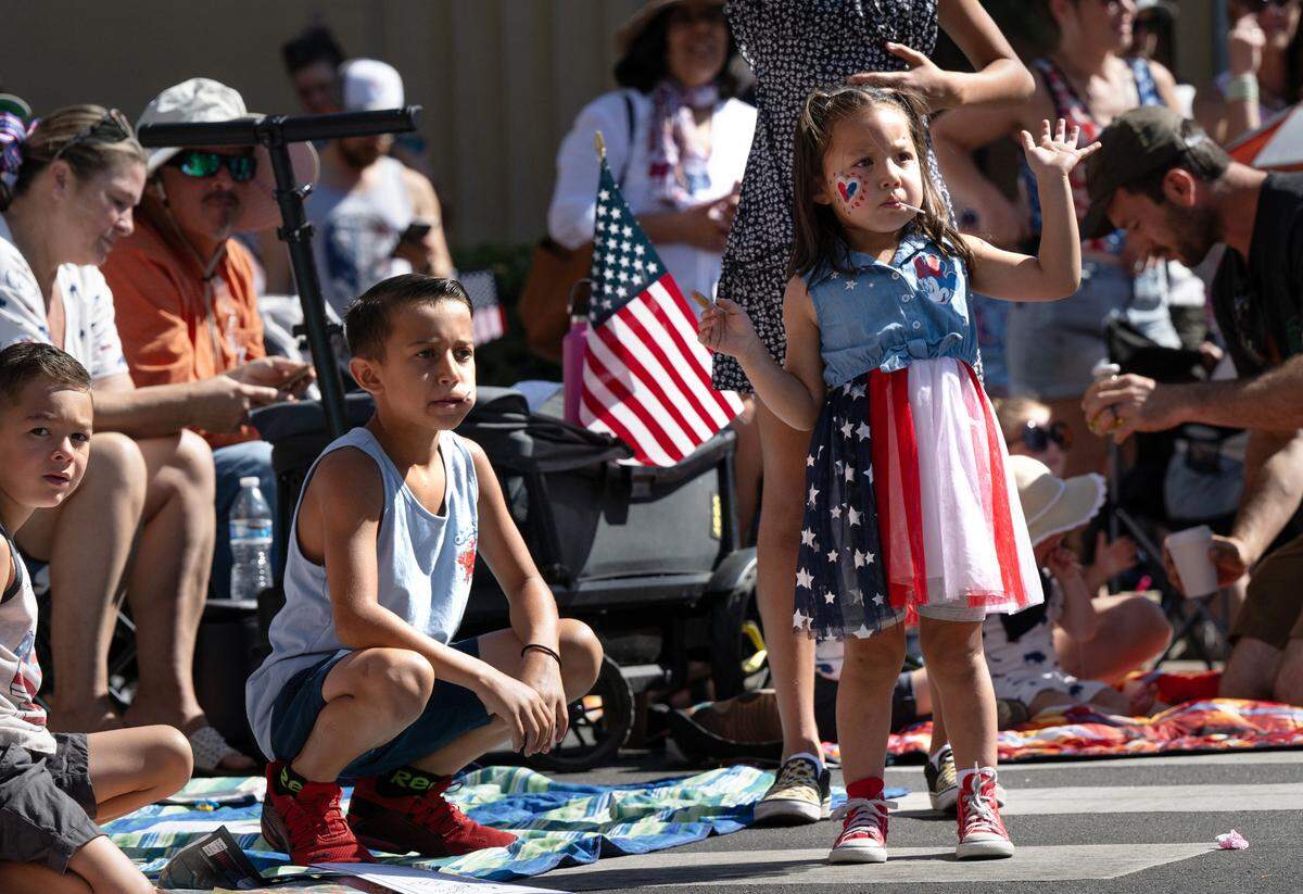 Ava Nayares, 4, and her brother Landon Middleton, 7, left, watch the Independence Day Parade on J Street as hundreds lined the downtown streets in Modesto, Calif., Tuesday, July 4, 2023.