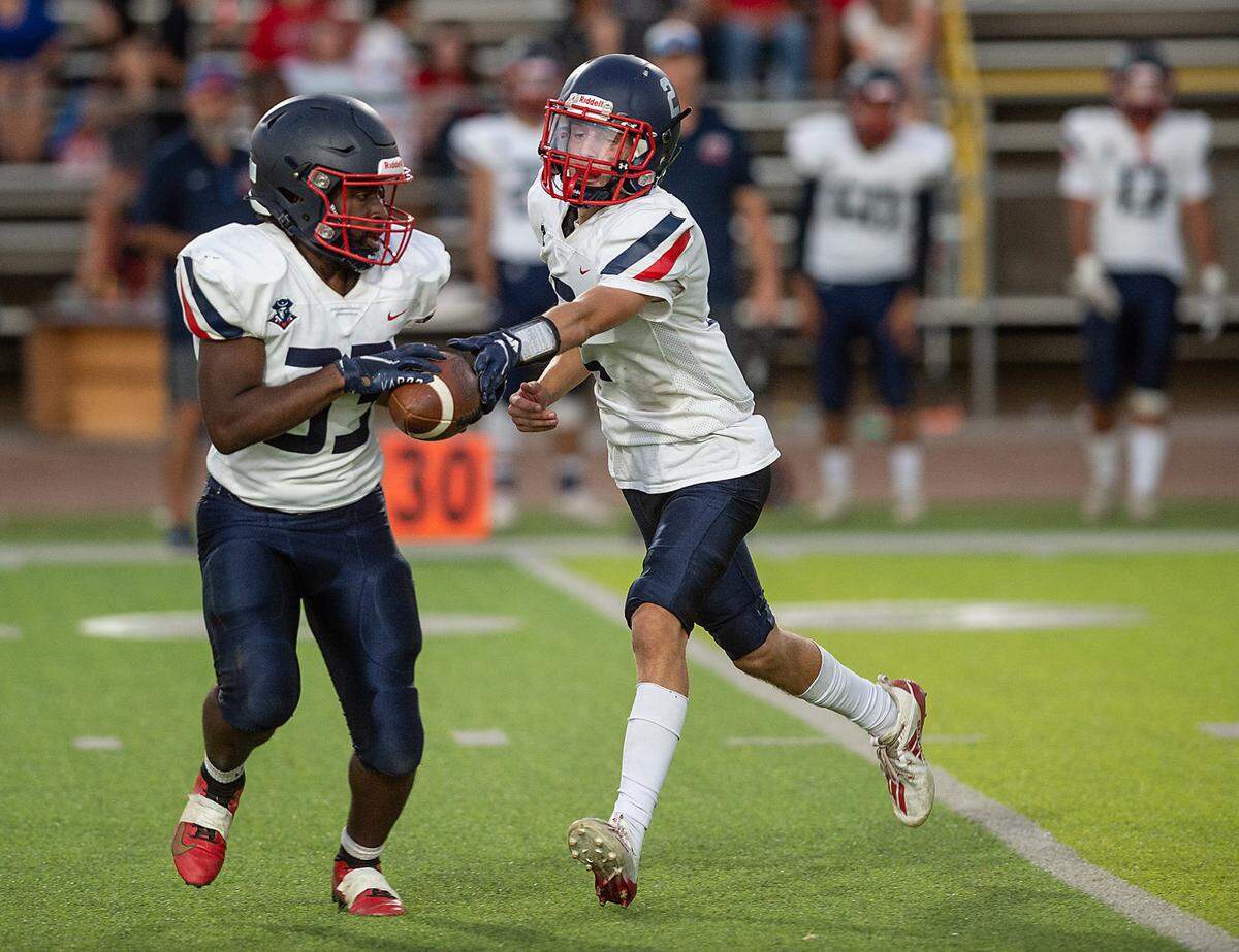 Beyer quarterback Brock Gross hands the ball off to Christopher Thomas during Friday’s game with Enochs at Downey High School in Modesto, Calif., on August 19, 2022.