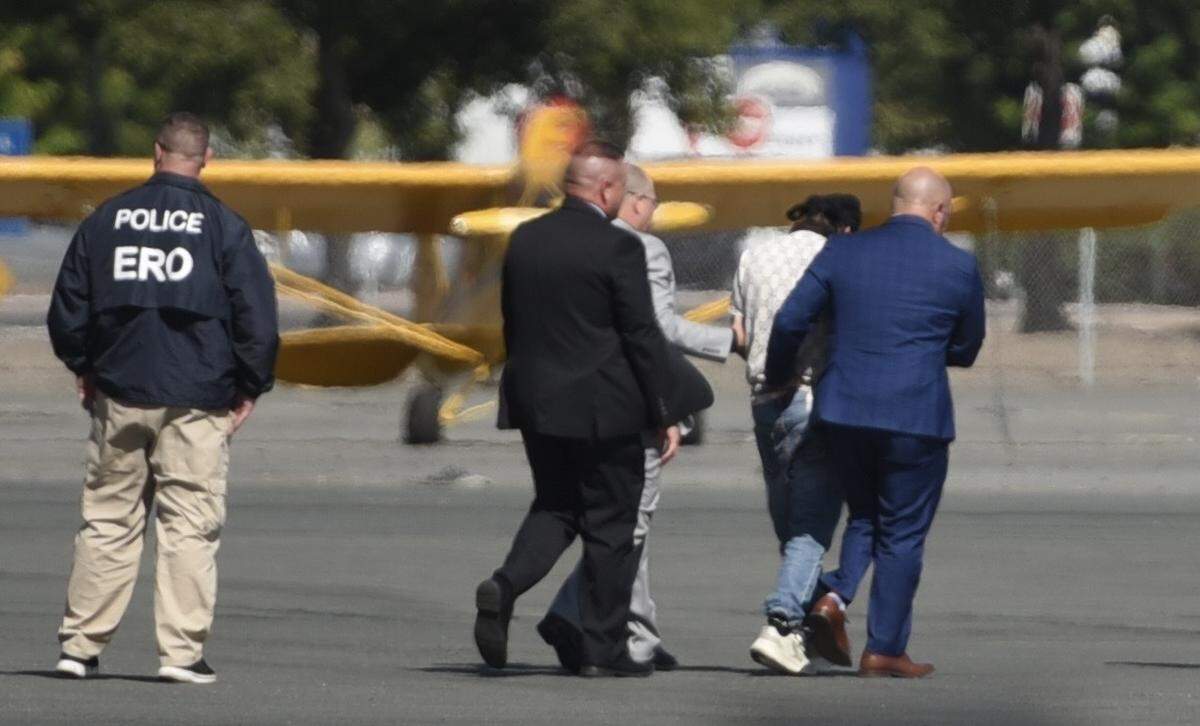 ICE officers and Lt. Gov. Jay Collins walk Harjinder Singh toward a waiting plane in Stockton for extradition to Florida.