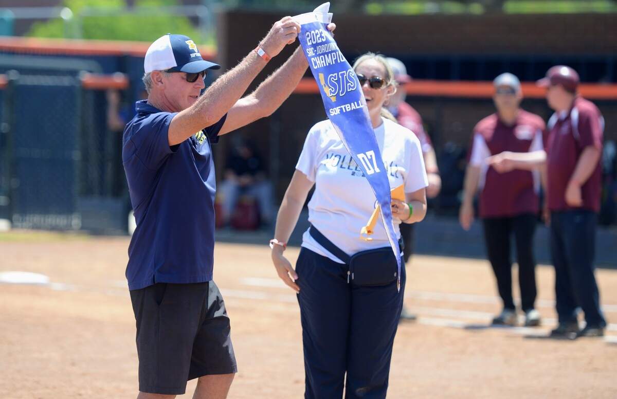 Big Valley Christian head coach Eric Layman receives the championship banner after the Lions won the Sac-Joaquin Section Division VII title at Cosumnes River College on May 18, 2024. It is their second title in three seasons.