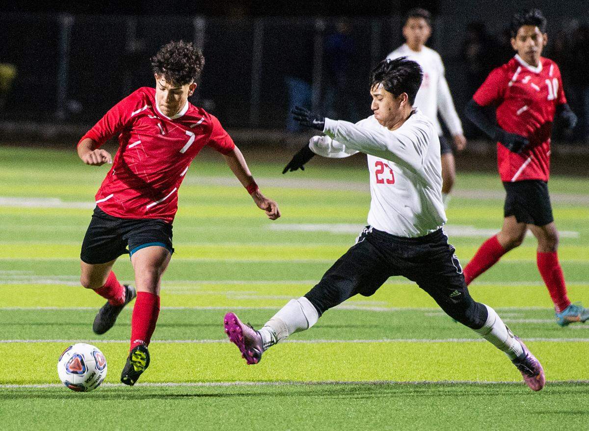 Modesto’s Brian Valenzuela Cabello takes a shot on goal as Lincoln’s Fernando Garcia (23) defends during the first round Division 1 Sac-Joaquin Section Playoff game with Lincoln High at Downey High School in Modesto, Calif., Tuesday, Feb. 14, 2023. Modesto won the game 3-2.