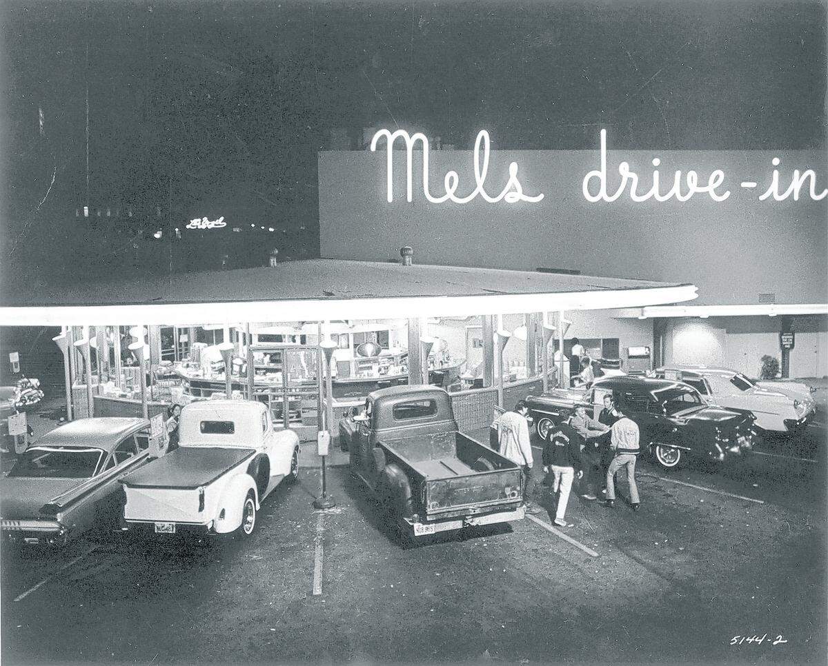 After cruising the boulevard, high schoolers congregate at their favorite hangout, Mel’s Drive-In, for a Double Chubby Chuck, french fries and a coke. A scene from the Lucasfilm Ltd./Coppola Company production for universal of “ American Graffiti.”