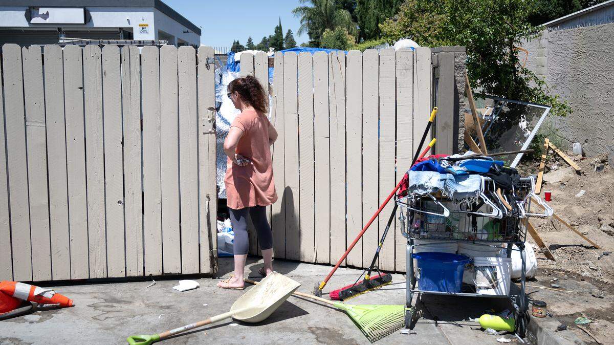 Lynelle Solomon, a homeless advocate and member of Modesto Citizens Action Group, talks with a person living behind retail shops along Yosemite Boulevard in Modesto, Calif., Thursday, July 6, 2023. Solomon often ventures out to help homeless individuals, packing her SUV with clothes, food, toothpaste, sandals, skin cream, and ice and cool water for hot days.