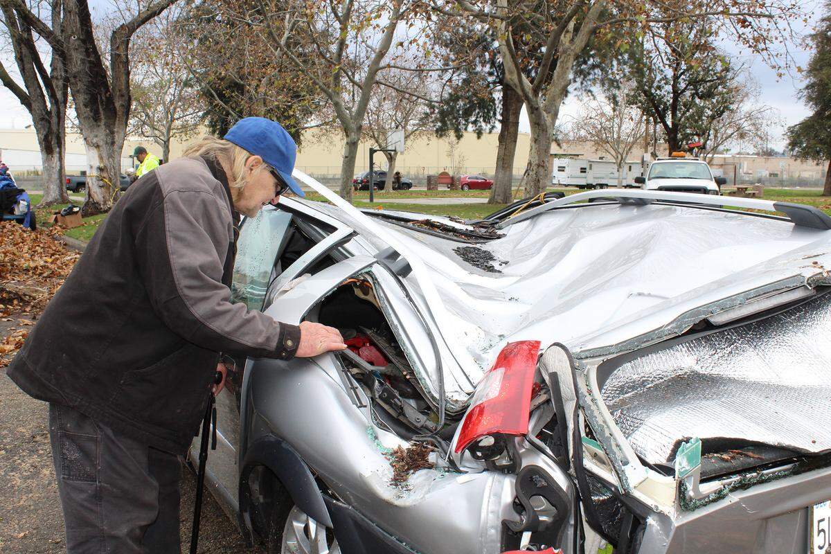 Bruce Wedin, 66, looks at the damage from a tree falling on his car at Broadway Park in Turlock, Calif., on Thursday, Dec. 16, 2021. Wedin was lying down in his car when it fell.