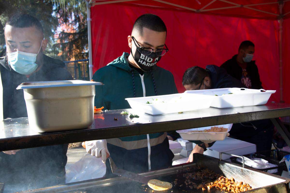 Samuel Contreras, owner of Tacos El Barbon (left), and Alex Sanchez, of Splash Bar, prepare tacos for the homeless on Thanksgiving Day 2020 in Graceada Park in Modesto, Calif.