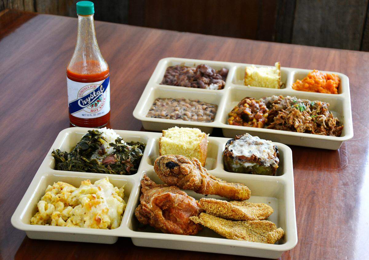 Two meat plates, one with fried chicken and fried catfish (front) and another with spicy creole pork, with assorted sides offered at the new Magnolia Southern Kitchen in Wood Colony, CA July 2, 2021.