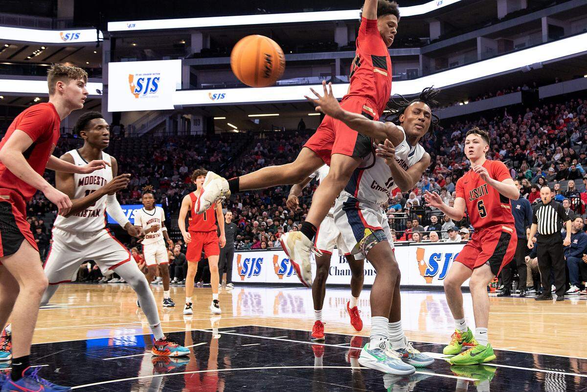 Modesto Christian’s Jeremiah Bernard passes the ball as Jesuit’s Ahjani Lewis defends during the Sac-Joaquin Section Division I championship game at Golden 1 Center in Sacramento, Calif., Saturday, Feb. 25, 2023.