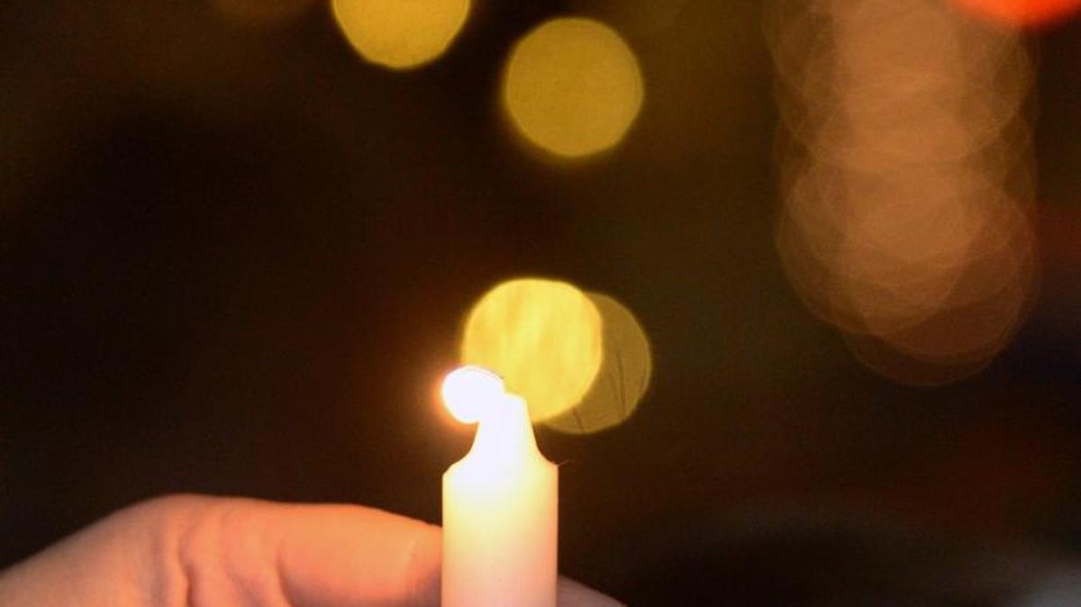 A candle is steadied the 2014 menorah lighting at Tenth Street Plaza in Modesto.
