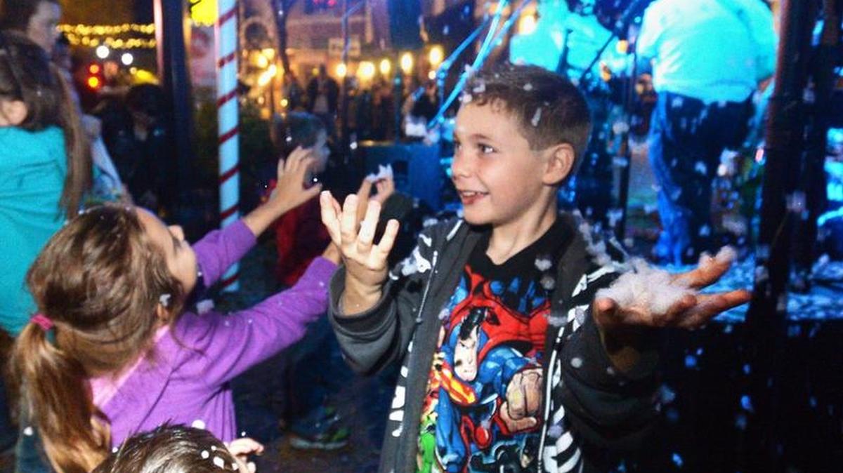 Kids including, at center, Nicolas Padilla II, age 8, of Modesto reach for the snow from an electric snow machine at the Rockin’ Holidays in 2014.