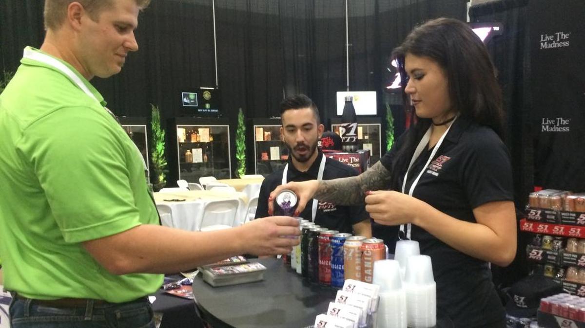 Destini Chumley pours a sample of a 51Fifty energy drink from Livingston for Zack Anderson during the Fresno Food Expo at the Fresno Convention & Entertainment Center, Thursday morning, July 27, 2017.