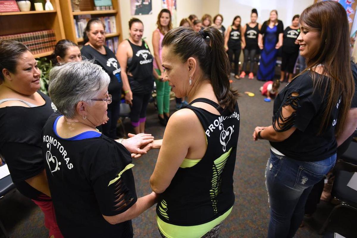 Rossy Gomar, center, shares a moment with Berta Maes during a promotoras meeting Wednesday, Sept. 9, 2015, at the Family Resource Center in Oakdale.