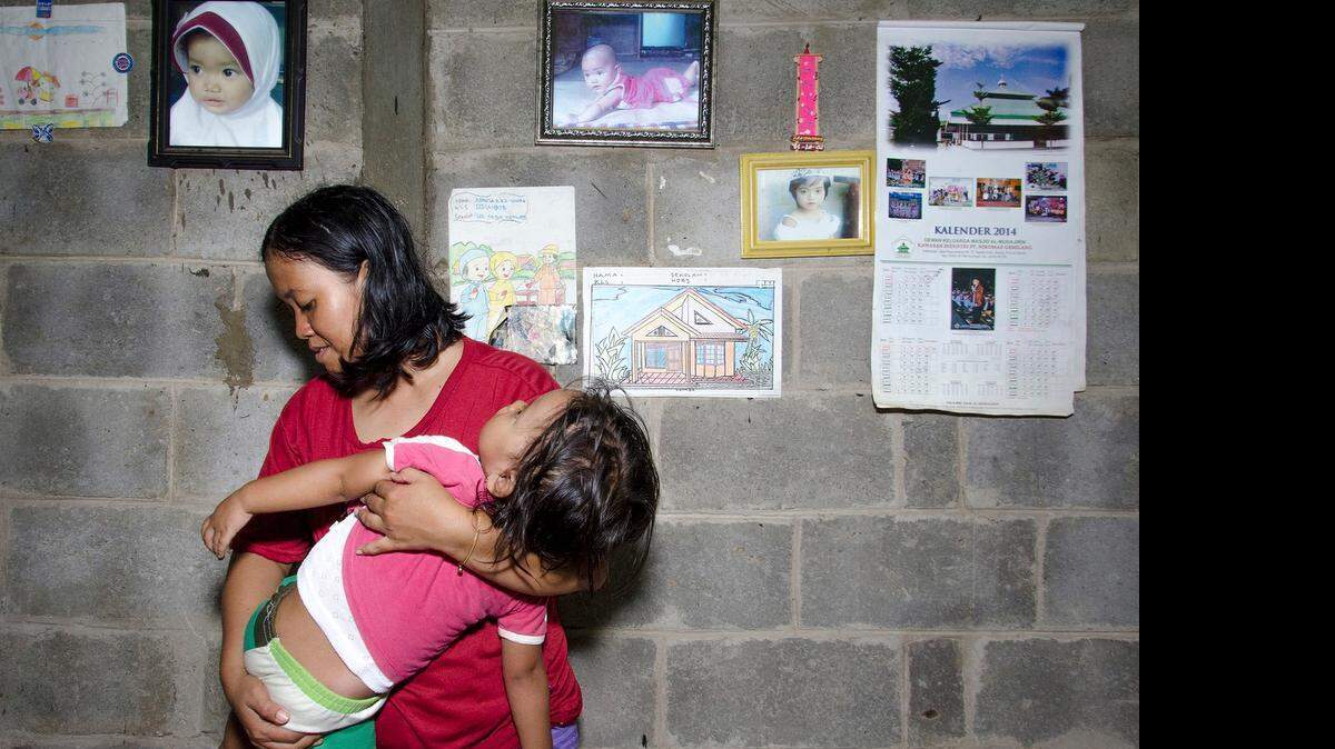 
Indonesian factory worker R.M. comforts her ill daughter at their home in Tangerang.
