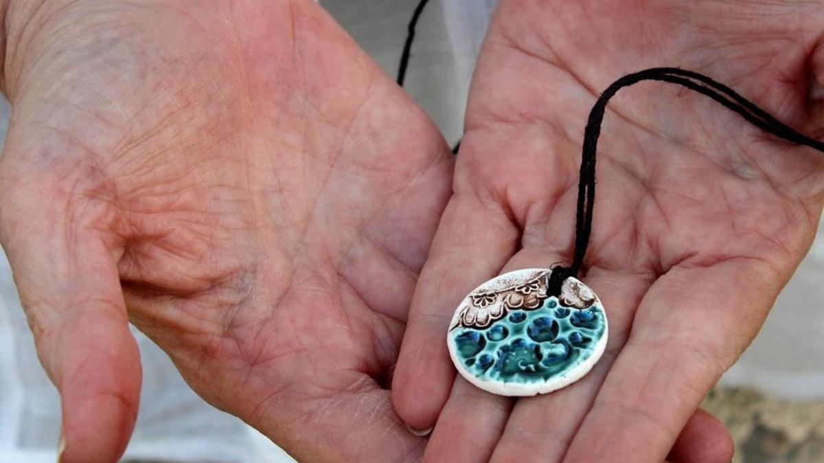 Erin Bell holds a ceramic essential oil diffuser that is worn as a necklace; a single drop of oil is placed on the back. Since ceramic is porous, the oil absorbs into the ceramic and slowly diffuses the aroma into the air, letting the wearer benefit while living an active lifestyle.