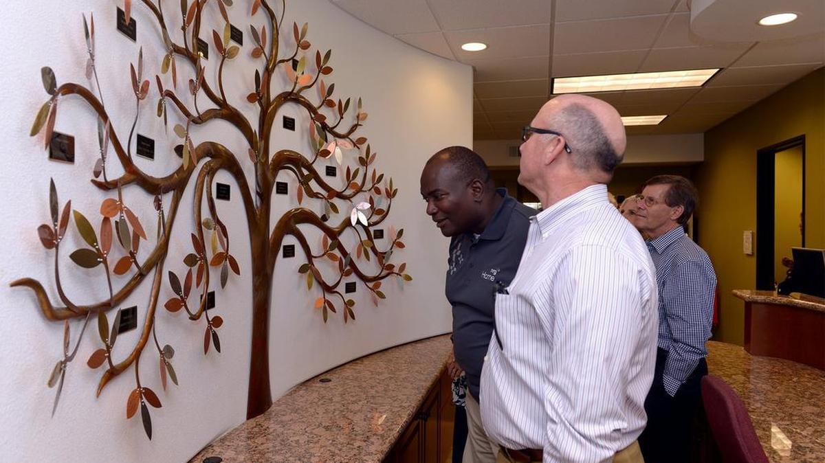 
Ross Lee, front, and Jeremiah Williams look at the giving tree on the wall during Wednesday’s tour of the new Center ror Human Services building in Modesto.
