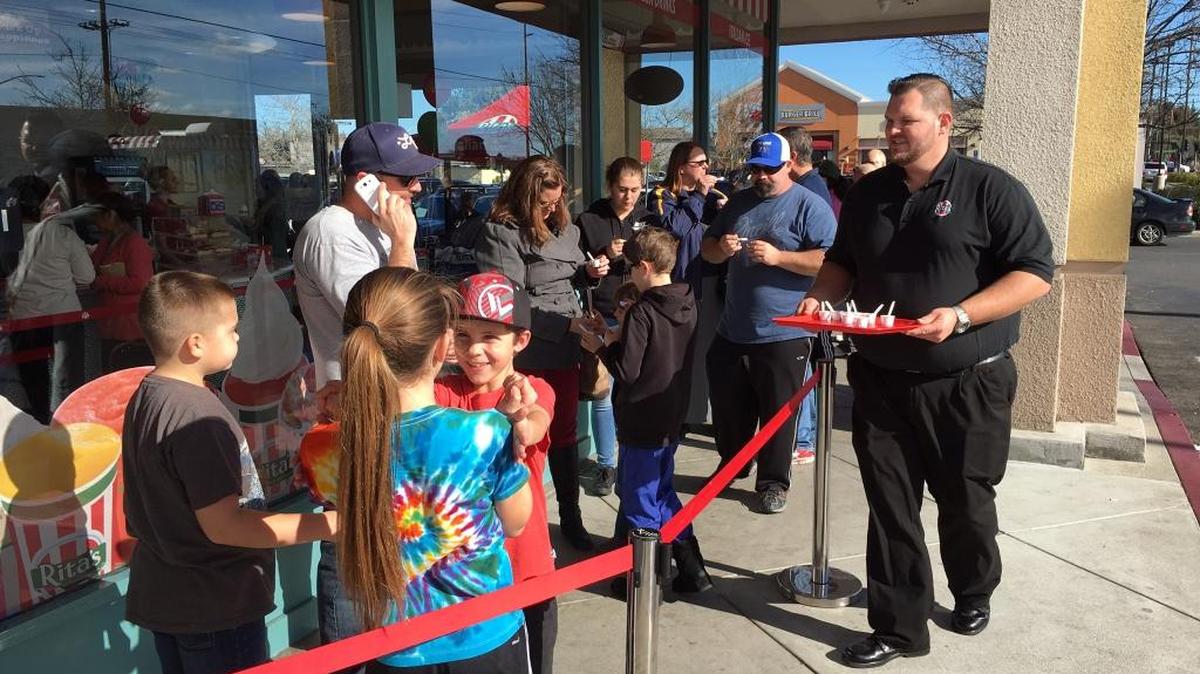 Nick Schutte, owner of Rita's Italian Ice on McHenry Avenue in Modesto, Calif. offers samples to people waiting in line Monday (01-18-16).