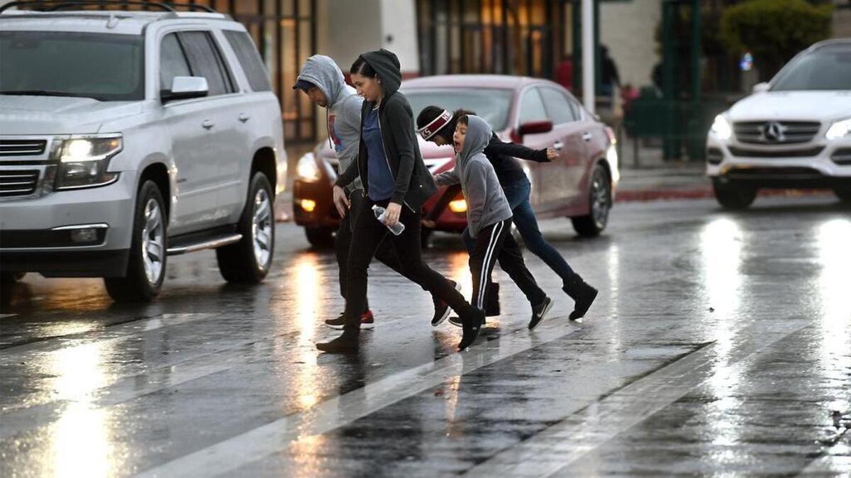 A family hurries through the rain to shop Friday afternoon at the Monte Vista Crossings shopping center in Turlock.