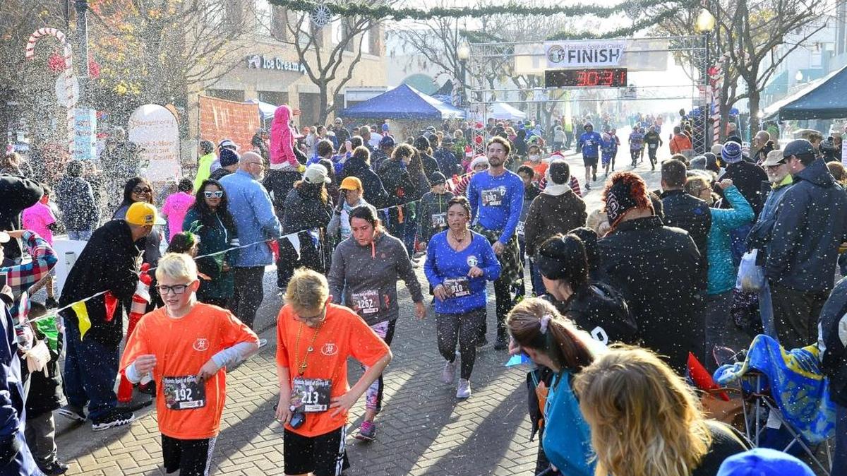 Runners in the 5K finish the race while artificial snow falls during the Modesto Spirit of Giving Run in downtown Modesto at 10th street plaza on December 9, 2017 in Modesto, CA.