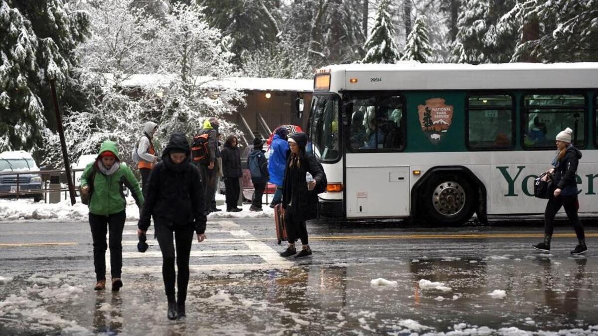 Visitors board and leave a Yosemite shuttle bus in January 2017 outside Yosemite Lodge in Yosemite National Park.
