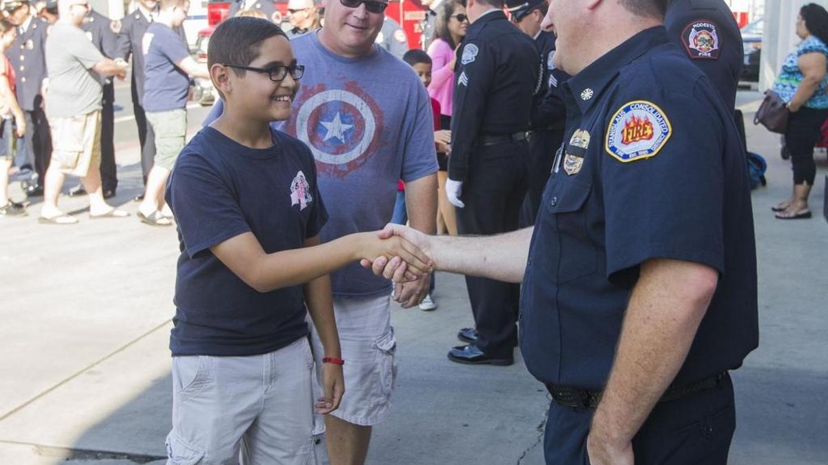 At a 9/11 remembrance held Sept. 11, 2016, at Modesto Fire Department Station 1, Maxwell Raymond, 12, and dad Steve Raymond shake hands with Stanislaus Consolidated Fire Chief Matt Daly.