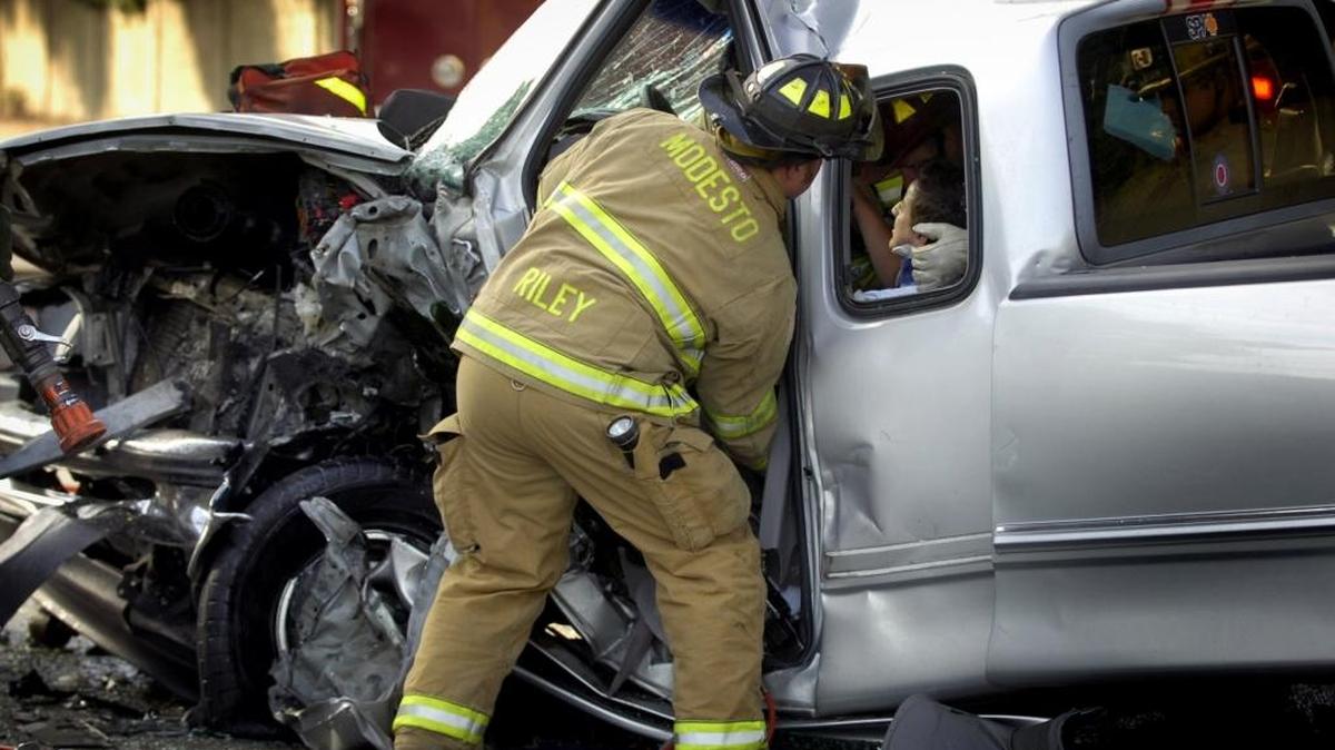 In this December 2010 file photo, a Modesto firefighter helps a teenage male vehicle accident victim on Scenic Drive.