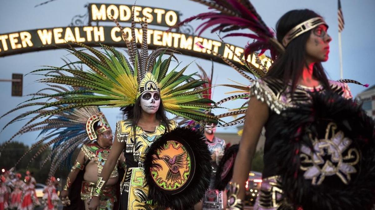 Members of the Azteca Dancers walk in the Dia de los Muertos procession on I Street in Modesto on Saturday, Oct. 24, 2015.