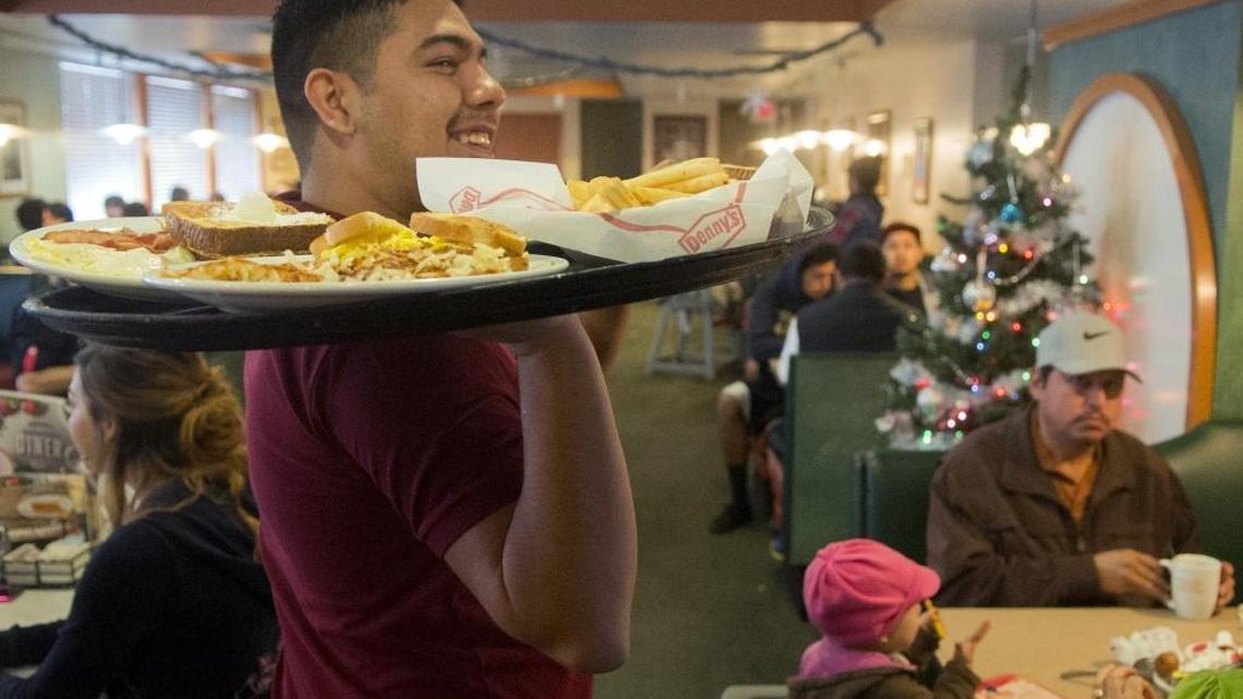 Denny’s server Francisco Martinez smiles as he holds a tray of food while working on Christmas Day at the McHenry Avenue restaurant in Modesto on Friday, Dec. 25, 2015.