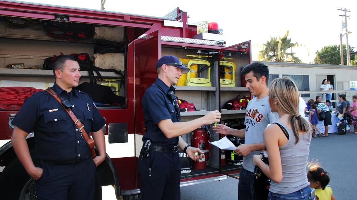Firefighters Joshua Brace, left, and Alex Roussell, middle, talk with Arturo Avila and Adelina Galvan during the Family Fun Night Safety & Health Fair on Friday, July 8, 2016.