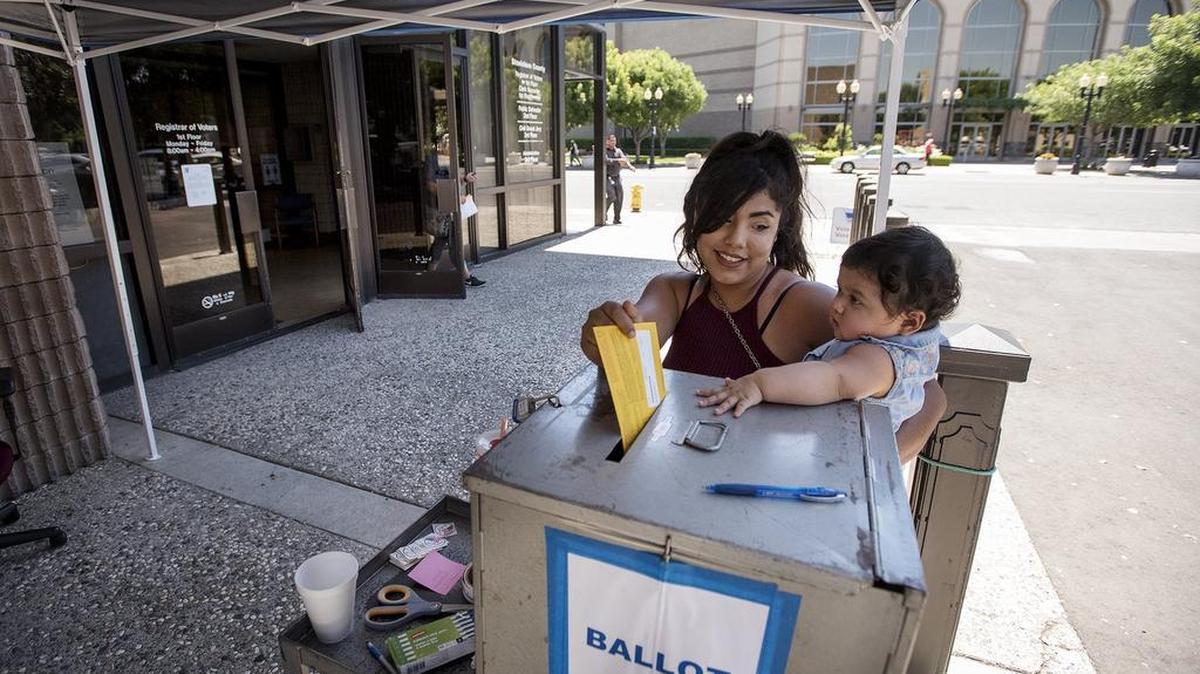 Alexis Arriola with her daughter Delilah, 1, drops off a ballot at the Stanislaus County Registrar of Voters office in Modesto, Calif., on Monday, June 6, 2016.
