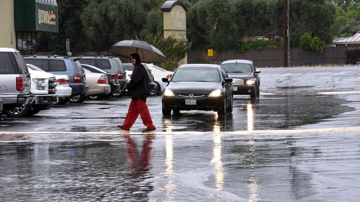 Jacob Polizzi makes his way through the puddles in the parking lot at McHenry Village in Modesto, Calif., on Friday afternoon, May 6, 2016. The area was hit with heavy rain that lasted from the morning into the afternoon.