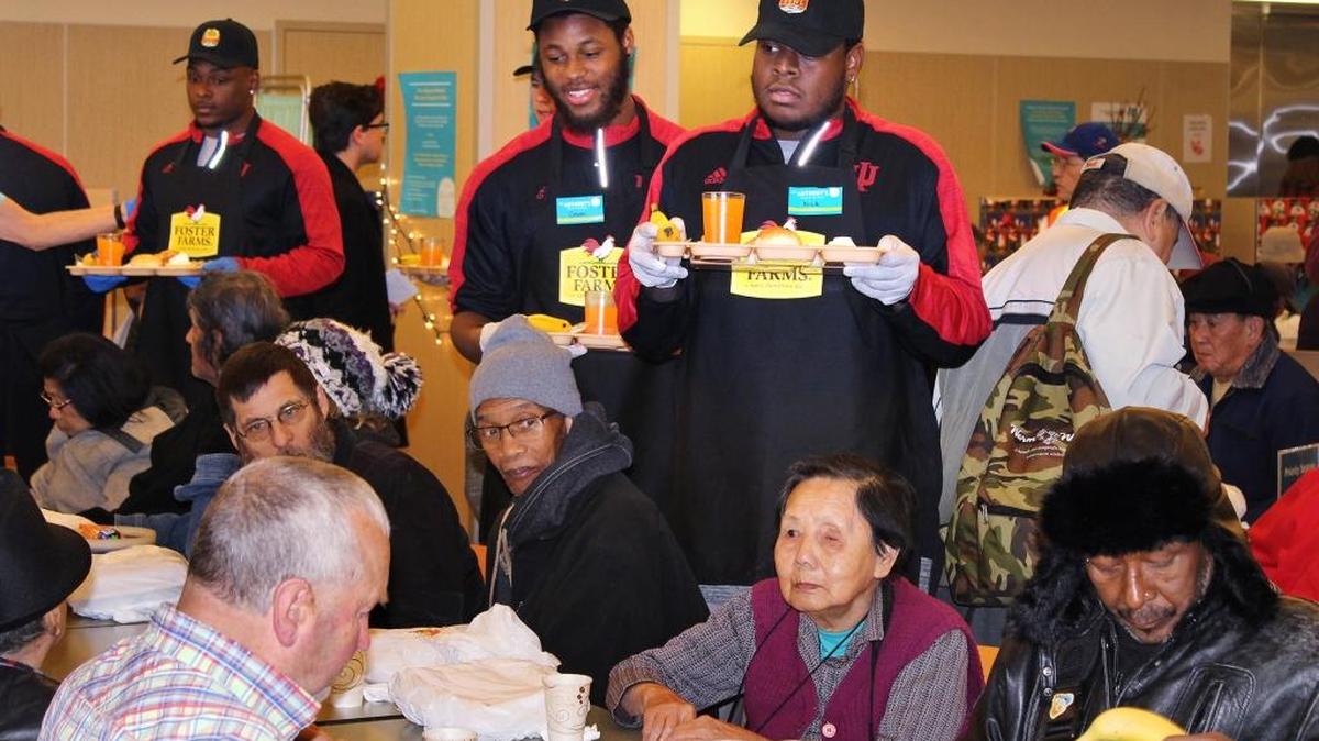 Omari Stringer, center left, and Nile Sykes are among Indiana players serving guests at St Anthony’s Dining Room in San Francisco. The teams playing in the Foster Farms Bowl on Wednesday, Dec. 28, 2016, volunteered on Christmas Day at two San Francisco charities that provide food to people in need. This is the third straight year that the Livingston-based poultry company has sponsored the college football game, which will be at Levi’s Stadium in Santa Clara. The game raises money for anti-hunger efforts.