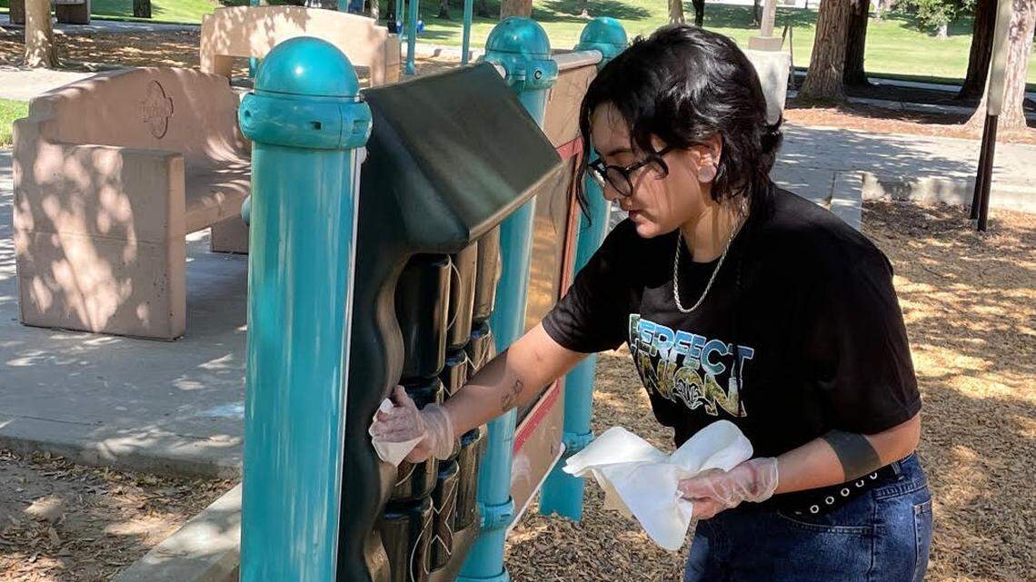 Angel Gaytan wipes down the play structure at Markley Park in Turlock CA as part of its adoption by the Perfect Union cannabis company on June 24, 2021.