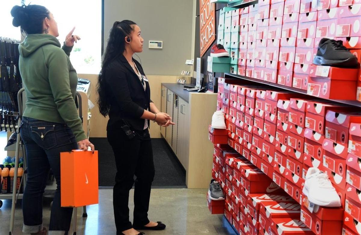 Employee Jaina Makai Kenolio, center, helps a customer shop for shoes Thursday morning at Rack Room Shoes in Monte Vista Crossings in Turlock, Calif.