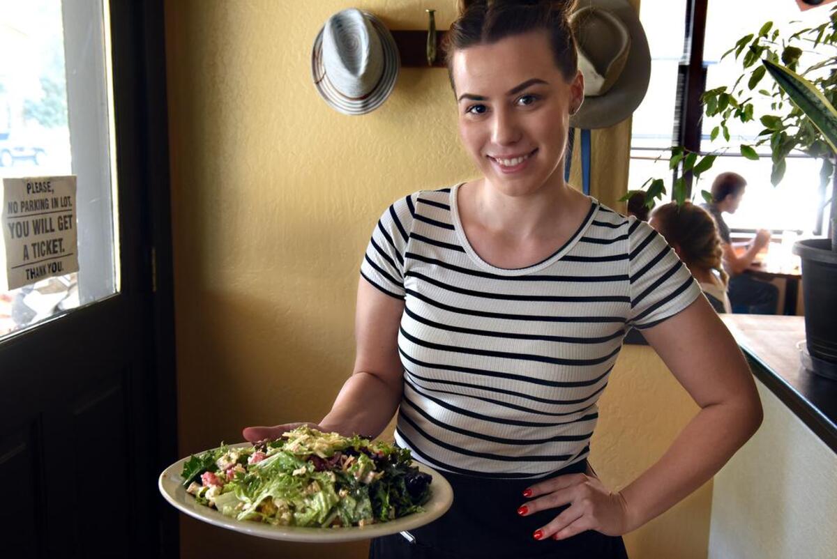 Server Hilary Borrelli holds a Neil’s Toss salad in October 2018 at Harvest Moon in downtown Modesto, Calif.