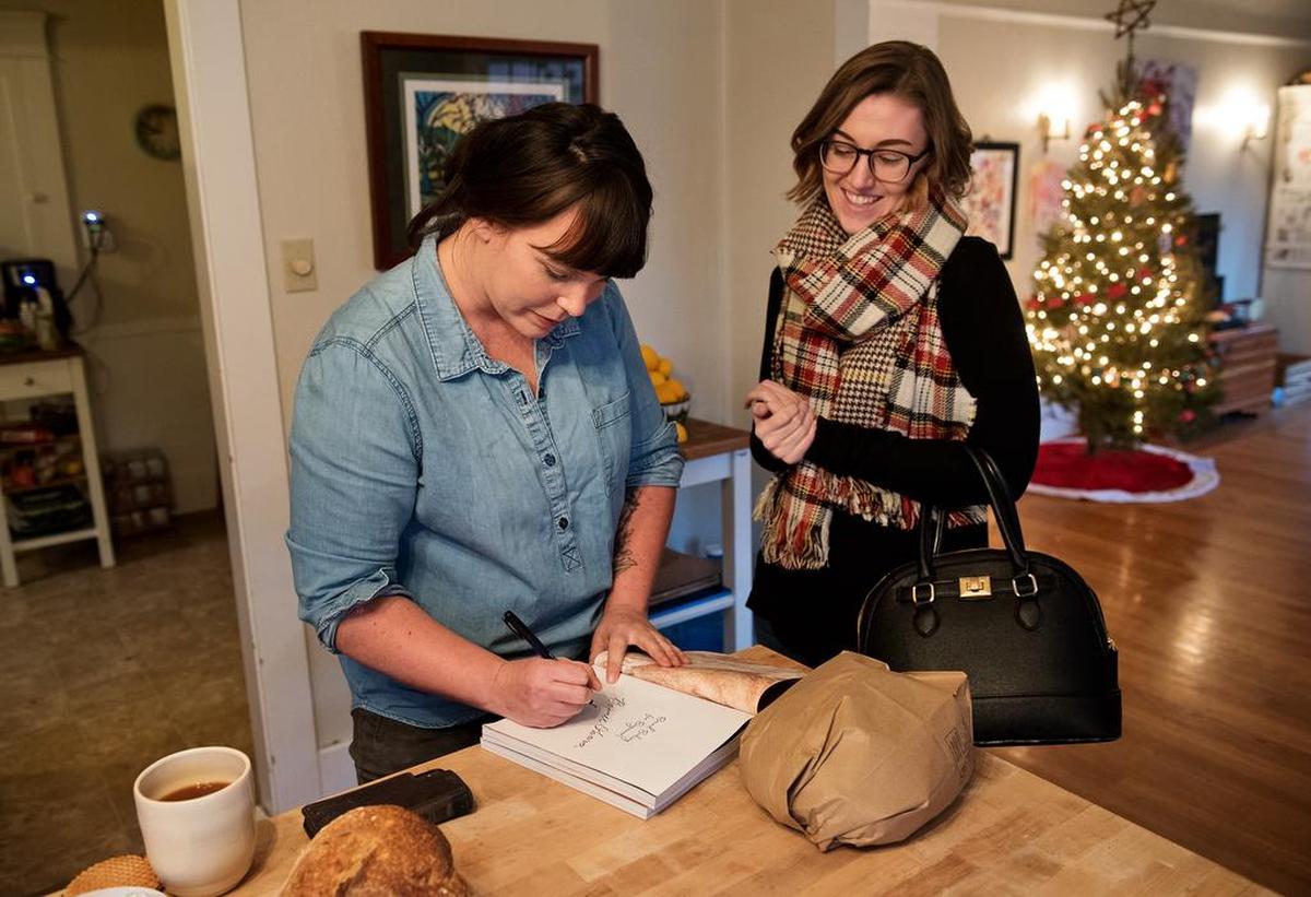 Local baker Bonnie Ohara signs her book “Bread Baking for Beginners” for T.J. Harrewyn, right, in Modesto, Calif., Thursday, Dec. 20, 2018.
