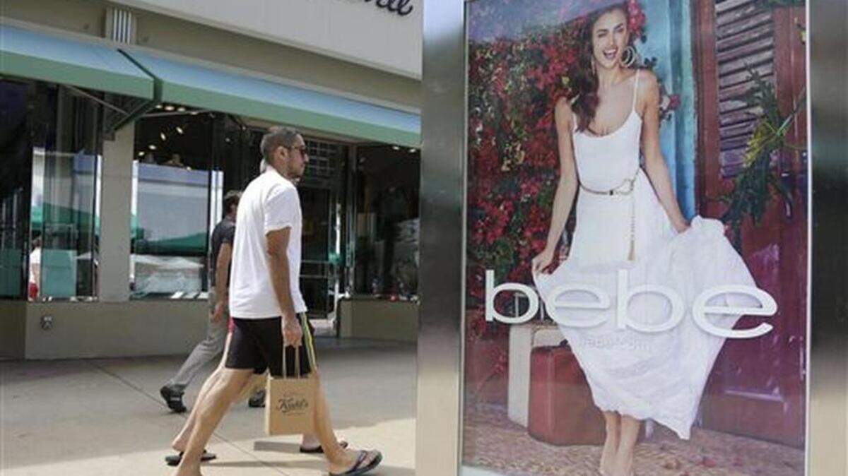 In this March 13, 2015 file photo, shoppers walk past an advertisement for retailer "bebe" at a mall in Miami.