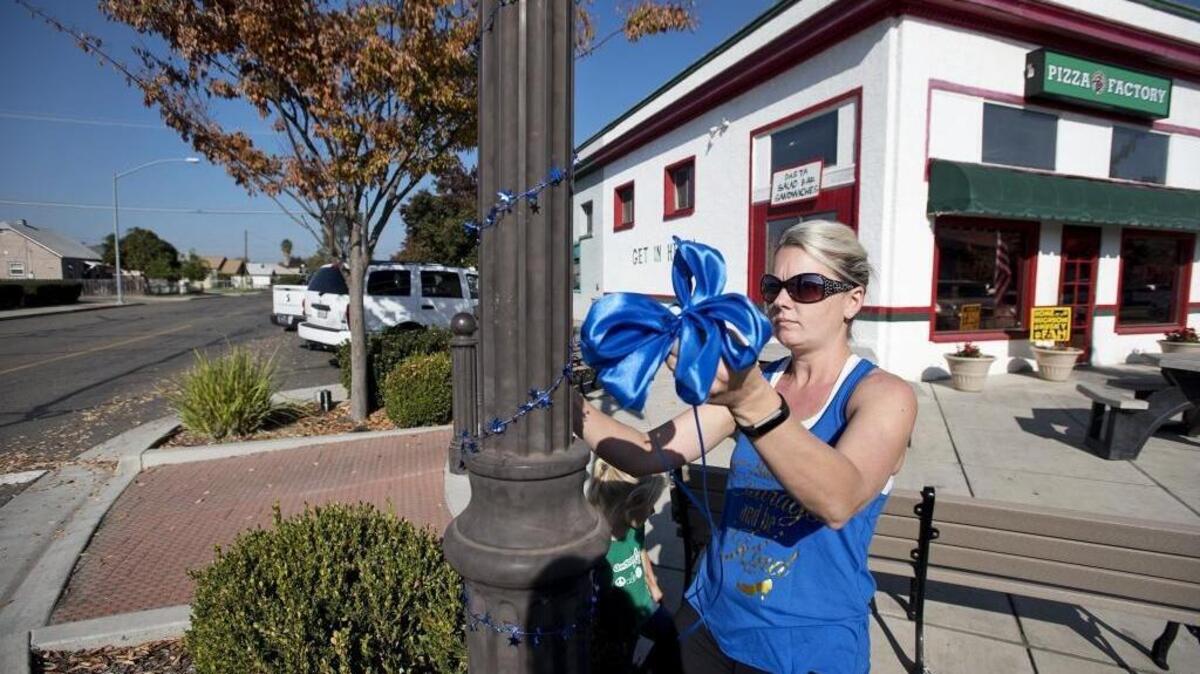 Amanda Young puts up blue ribbons and a bow in memory of slain sheriff’s Deputy Dennis Wallace in Hughson on Nov. 14.